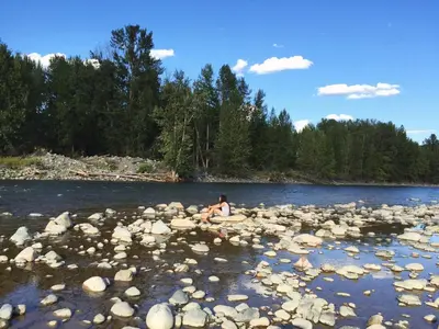 a person sitting on a rock in the middle of a river at Evergreen Motel in Princeton