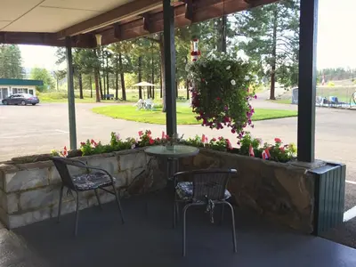 a patio with two chairs and a table and flowers at Evergreen Motel in Princeton
