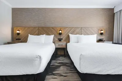 two beds in a hotel room with white sheets at Sandman Hotel & Suites Kelowna in Kelowna