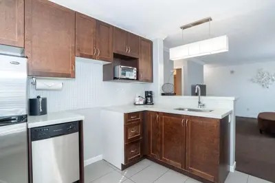 a kitchen with wooden cabinets and a sink at Sandman Hotel & Suites Kelowna in Kelowna