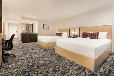 a hotel room with two beds and a desk at Executive Suites Hotel & Conference Center, Metro Vancouver in Burnaby