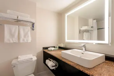 a white bathroom with a sink and a mirror at Executive Suites Hotel & Conference Center, Metro Vancouver in Burnaby
