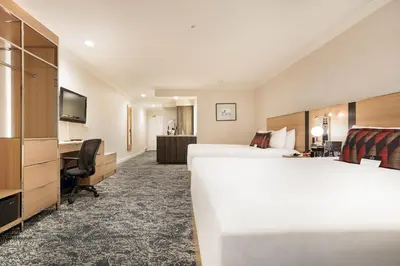 a hotel room with two beds and a desk at Executive Suites Hotel & Conference Center, Metro Vancouver in Burnaby