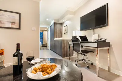 a room with a table with a wine glass and a desk at Executive Suites Hotel & Conference Center, Metro Vancouver in Burnaby
