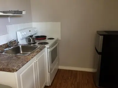 a small kitchen with a sink and a stove at Sun Plaza Motel in Sundre