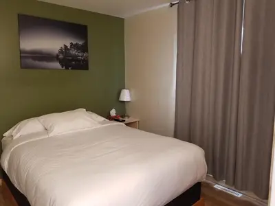 a bedroom with a white bed and a window at Sun Plaza Motel in Sundre