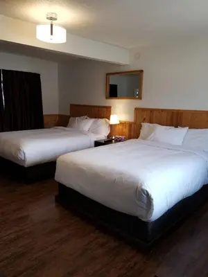 a hotel room with two beds and a tv at Sun Plaza Motel in Sundre