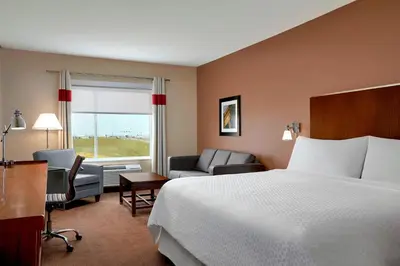 a hotel room with a bed and chairs and a window at Four Points by Sheraton Sherwood Park in Sherwood Park