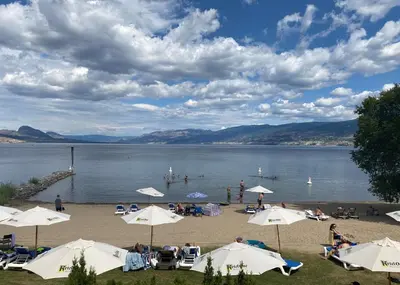 a group of people on a beach with umbrellas at Penticton Lakeside Resort in Penticton