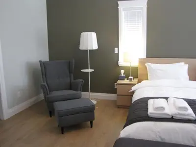 a bedroom with a bed and a chair and a lamp at Riverfront Bed and Breakfast in North Vancouver