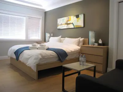 a bedroom with a bed with white sheets and a table at Riverfront Bed and Breakfast in North Vancouver