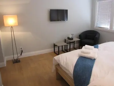 a bedroom with a bed and a chair and a television at Riverfront Bed and Breakfast in North Vancouver
