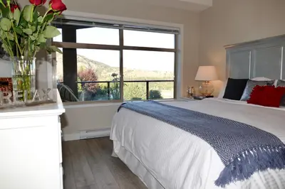 a bedroom with a bed and a large window at Copper Oasis in West Kelowna