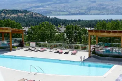 a swimming pool with chairs and a view of a lake at Copper Oasis in West Kelowna