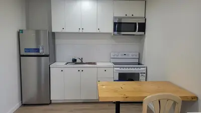 a kitchen with white cabinets and a wooden table at Riverside Inn in Wabasca
