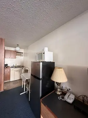 a kitchen with a refrigerator and a table with a lamp at Howard Johnson by Wyndham Edson in Edson