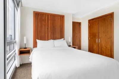 a bedroom with a white bed and wooden cabinets at Embarc Vancouver in Vancouver