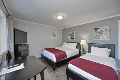 a hotel room with two beds and a desk at Maple Leaf Motel & RV Park Resort in Oliver
