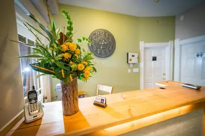 a vase of flowers on a wooden table with a cell phone at Cloudside Hotel in Nelson