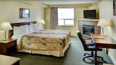 a hotel room with a bed and a fireplace at Nova Inn Peace River in Peace River