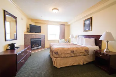 a hotel room with a bed and a fireplace at Nova Inn Peace River in Peace River