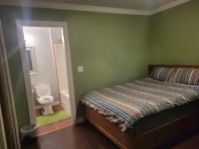 a bedroom with a bed and a toilet in a bathroom at Vancouver Jenny's Guesthouse in Coquitlam