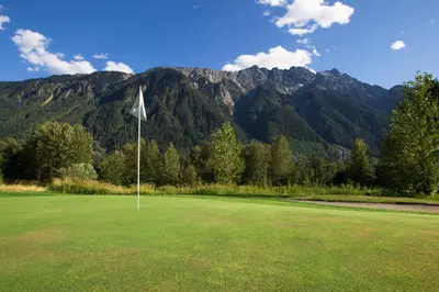 a golf course with mountains in the background and a flag at Mountainview 1 bedroom suite with check in services king size bed walk to Village WIFI cable TV free parking boot and glove warmer in Pemberton