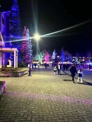 a group of people walking around a plaza with christmas lights at Mountainview 1 bedroom suite with check in services king size bed walk to Village WIFI cable TV free parking boot and glove warmer in Pemberton