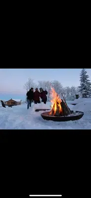 a group of people standing around a fire in the snow at Heart West Haven in Priddis