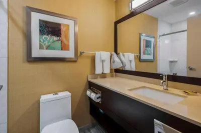 a bathroom with a sink and a toilet and a mirror at Best Western Plus Chateau Fort St. John in Fort Saint John