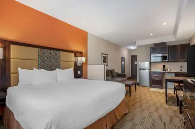 a hotel room with a large bed and a kitchen at Best Western Plus Chateau Fort St. John in Fort Saint John