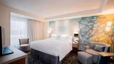 a hotel room with a bed and a desk and chair at Hotel Dene & Conference Centre in Cold Lake