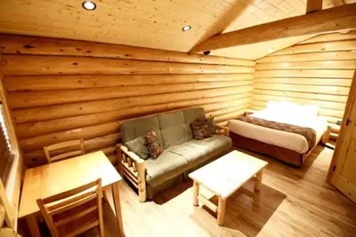 a room with a bed and a couch in a log cabin at Port Hardy Cabins in Port Hardy