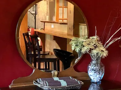 a vase of flowers on a table in front of a mirror at Mistiso's Place in Nelson
