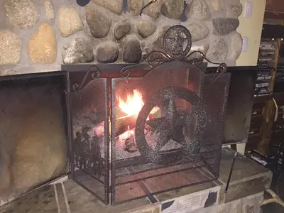 a stone fireplace with a fire in it at Montana Hill Guest Ranch in Bridge Lake