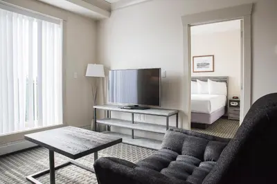 a living room with a couch and a tv and a bed at Chateau Nova Yellowknife in Yellowknife
