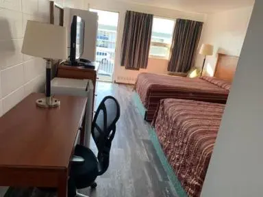 a hotel room with a desk and a room with two beds at Raven Motor Inn in High Prairie