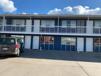 a car parked in a parking lot in front of a building at Raven Motor Inn in High Prairie