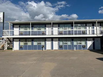 a large building with a parking lot in front of it at Raven Motor Inn in High Prairie