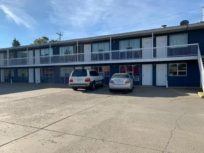 two cars parked in a parking lot in front of a building at Raven Motor Inn in High Prairie