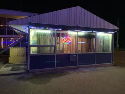 a neon sign in the window of a restaurant at night at Raven Motor Inn in High Prairie