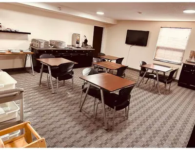 a classroom with tables and chairs and a flat screen tv at Aurora Park Inn & Suites in Dawson Creek