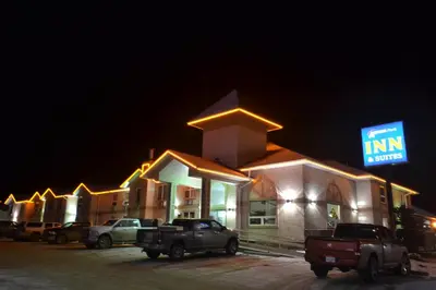 a inn with trucks parked in front of it at night at Aurora Park Inn & Suites in Dawson Creek