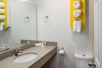 a bathroom with a sink and a toilet and a mirror at Motel 6-Fort Nelson, BC in Fort Nelson