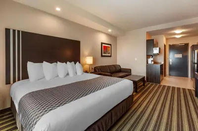 a hotel room with a large bed and a couch at Best Western Plus Drayton Valley in Drayton Valley