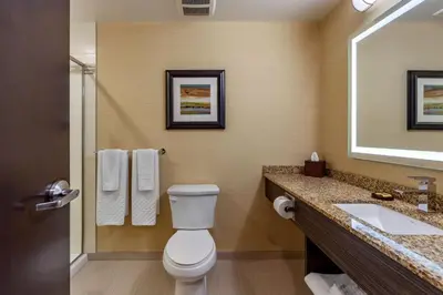 a bathroom with a toilet and a sink and a mirror at Best Western Plus Drayton Valley in Drayton Valley