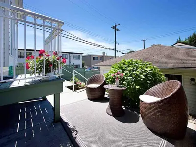 a patio with three chairs and a table and some flowers at Marpole Guest House in Vancouver