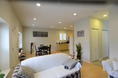 a living room with a white couch and a kitchen at Marpole Guest House in Vancouver