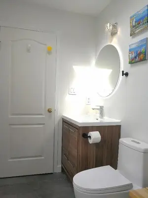 a bathroom with a toilet and a sink and a mirror at Marpole Guest House in Vancouver