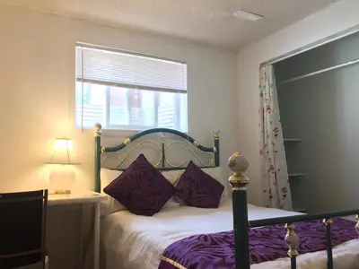 a bedroom with a bed with purple pillows and a window at Calgary Star Cozy Home in Calgary